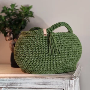Panier en crochet fait main, coloris vert mousse avec fil doré scintillant, doté d’une anse et d’un petit pompon décoratif, et l'estampille en cuir de la marque bobinensac