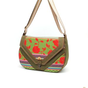 Sac bandoulière Mirabelle en toile à sac kaki avec rabat en tissu d’ameublement tissé rouge, doublure rouge et sangle large en polyester rayée kaki, blanc et doré.